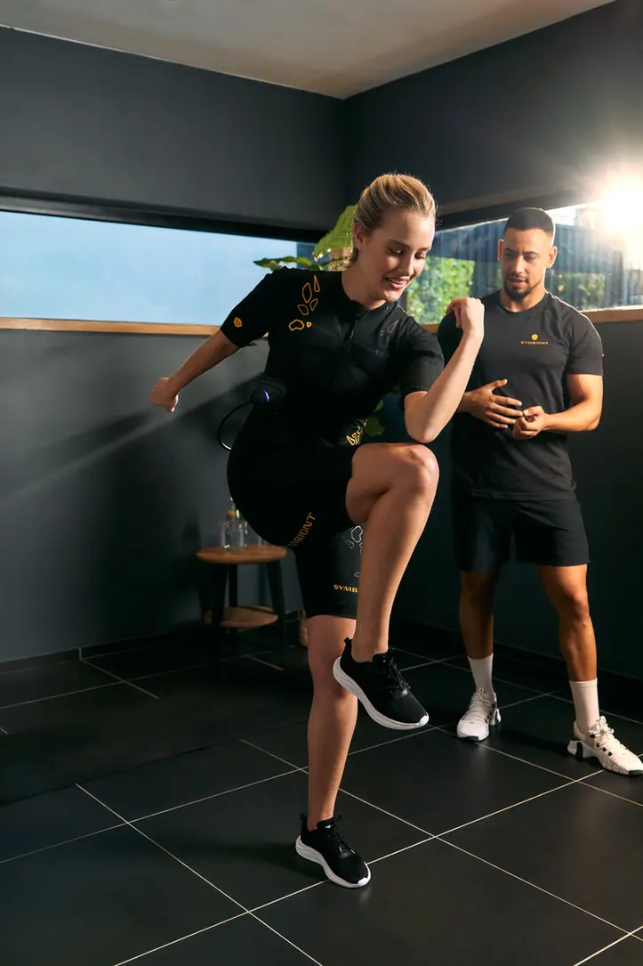 Experimente o treino SYMBIONT no seu estúdio TechBody Personal trainer a orientar um cliente com um fato SYMBIONT durante uma sessão de teste num estúdio TechBody. Experimente treino personalizado com eletroestimulação SYMBIONT..